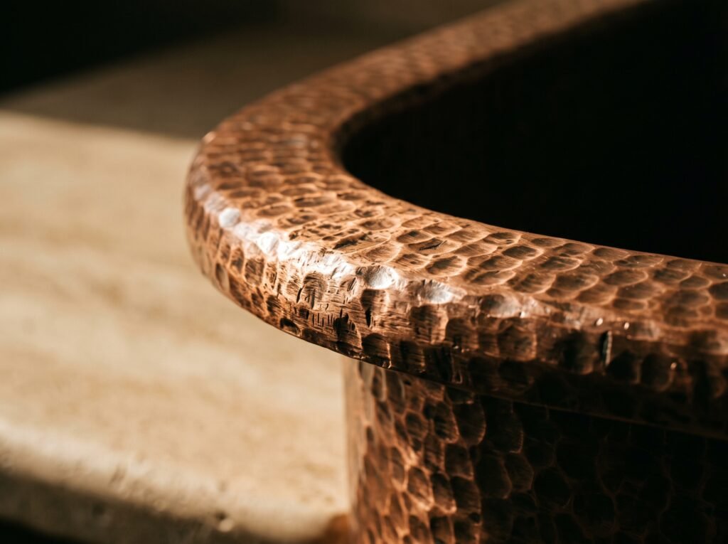 Close-up of the thick rolled rim of a hand-hammered copper sink