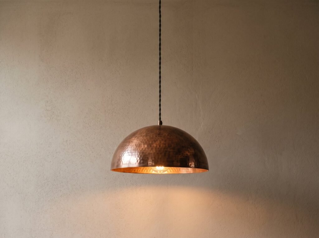 Copper dome pendant light hanging against a pale plaster wall